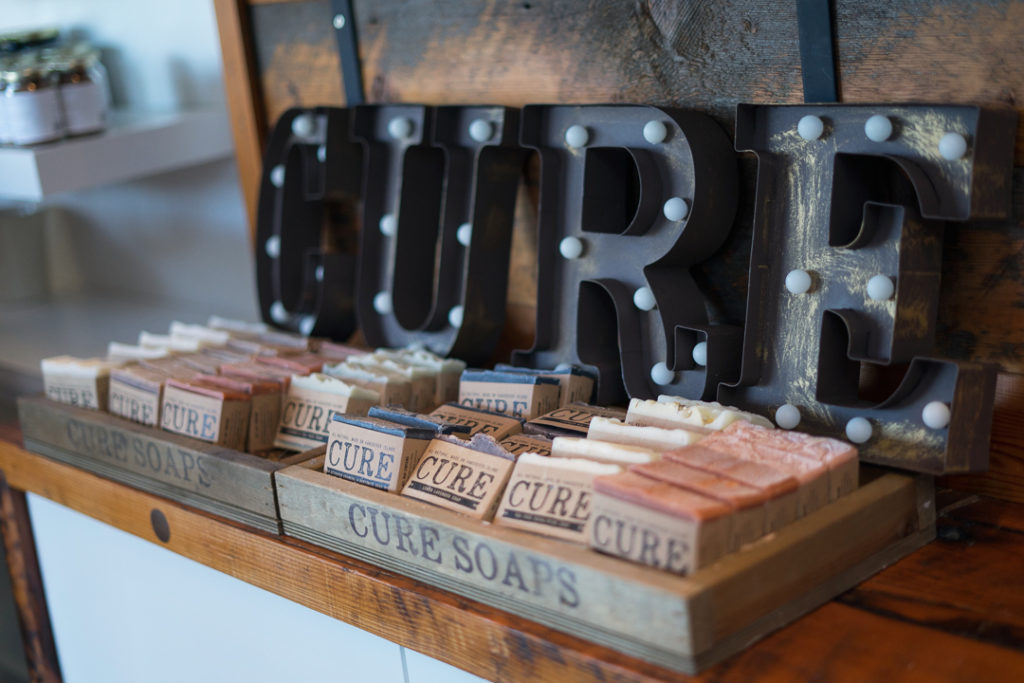 Image of a variety of soap bars with the word CURE against stained wood.