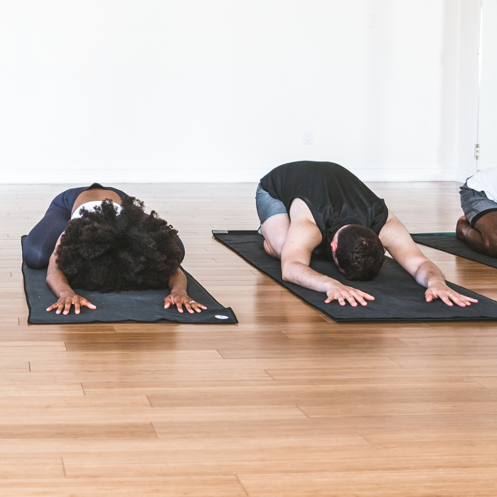 A group of people lie in child's pose on the floor