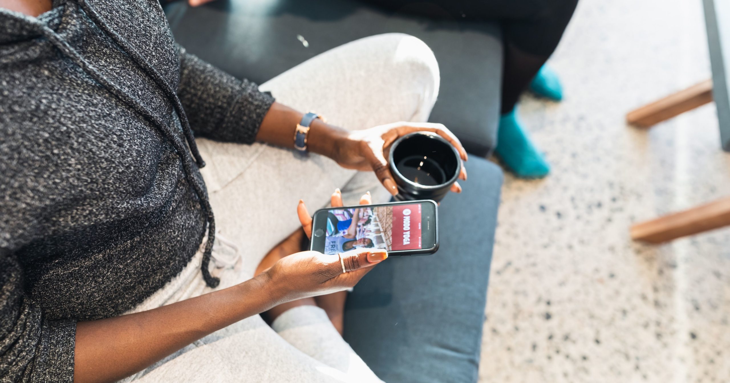 A student is using the Modo Yoga App to register for class while drinking tea