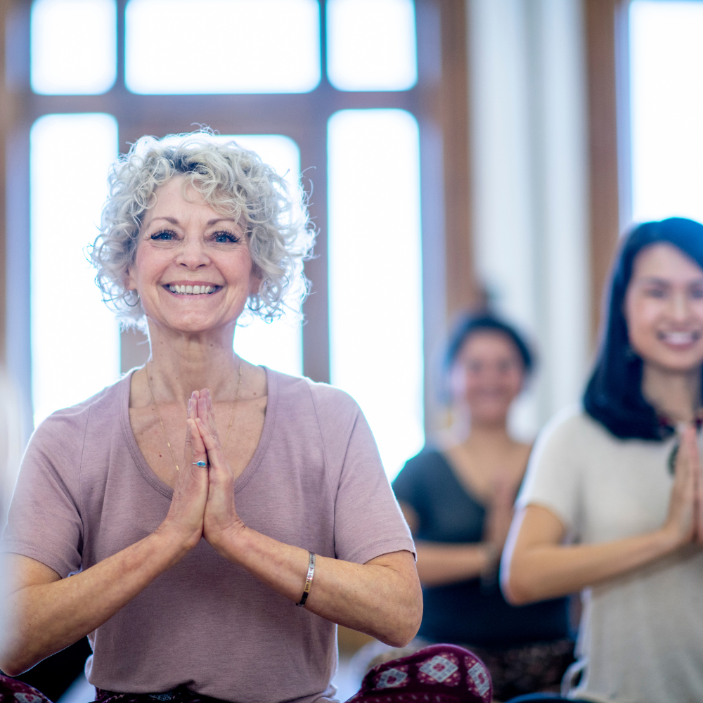 Photo of an elderly woman in prayer pose.